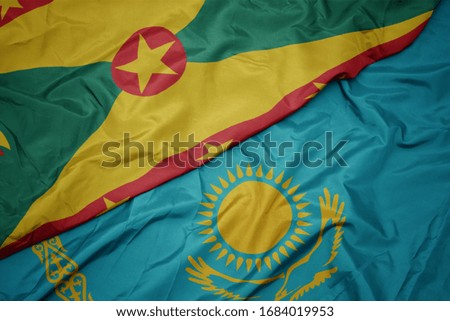 waving colorful flag of kazakhstan and national flag of grenada. macro