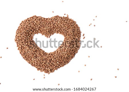 Buckwheat in the shape of a heart isolated on background. Love for buckwheat porridge. Buckwheat groats, seeds. Useful gluten-free cereal. Close-up, top view with copyspace