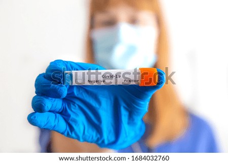 a doctor holds a coronavirus smear tube in her hand