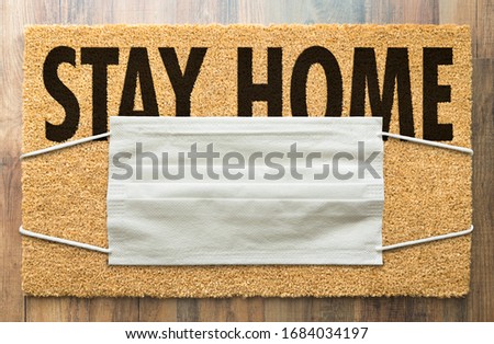 Welcome Mat With Medical Face Mask and Stay Home Text Amidst The Coronavirus Pandemic. Royalty-Free Stock Photo #1684034197