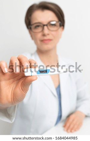 Portrait of a doctor woman showing a thermometer measuring temperature.