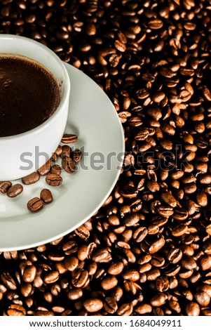 cup of coffee over a lot of coffee beans background 