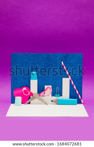 Scissors, marker and other decorations on a purple and shiny blue background