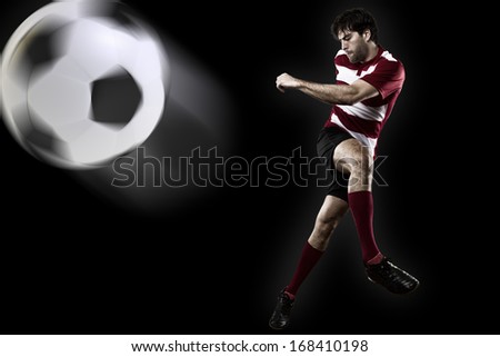 Soccer player in a red uniform kicking. Black Background