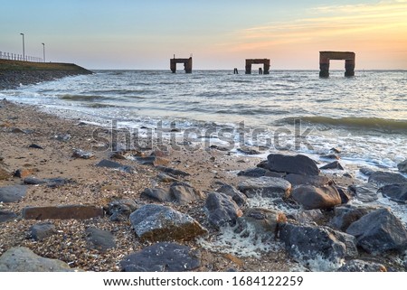 scenic wide angle picture of the ruins of the former landing bridge in Eckwarderhörne (district Wesermarsch, Germany) during a beautiful sunset over the bay Jadebusen