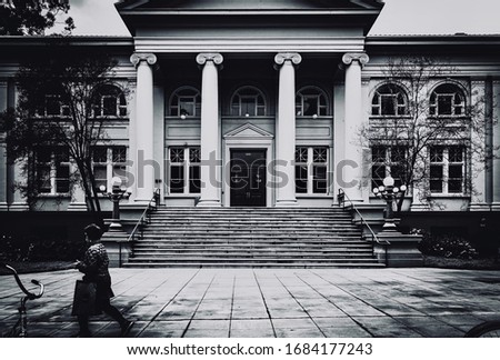 Black and white photo of The Carnegie Hall library building architecture as a woman walks by in the southern California city of Claremont, California.￼ architecture photograph.￼