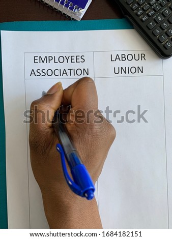 A Black person completing a document that has two columns: employees association and labour union