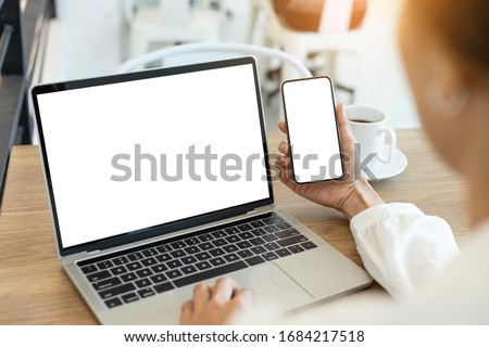 computer,cell phone mockup image blank screen with white background for advertising text,hand woman using laptop texting mobile contact business search information on desk in cafe.marketing,design Royalty-Free Stock Photo #1684217518