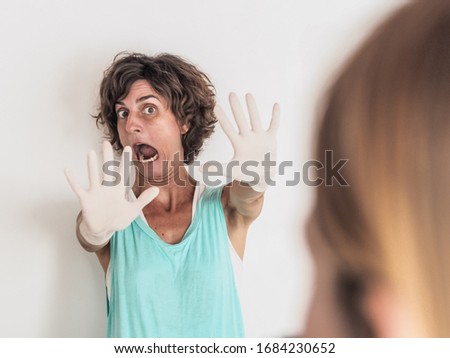 worried and fearful woman social distancing from corona virus covid-19 wearing medical gloves holding up hands saying stop to another person Royalty-Free Stock Photo #1684230652