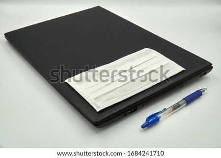 Blue pen, face mask and black against white background                               