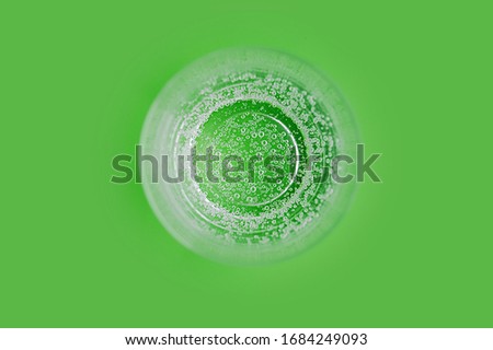picture about a healthy lifestyle. Clear glass water glass full of pure carbonated water with bubbles on a clear green background. Top view