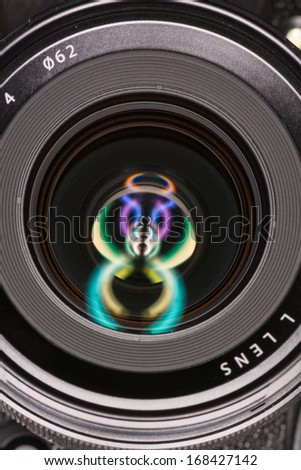 Macro shot of front element of a camera lens with beautiful color lights reflections 