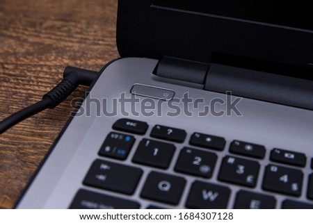 Laptop, computer is charging from a 220-volt outlet on a desk near the wall. Energy, accumulation
