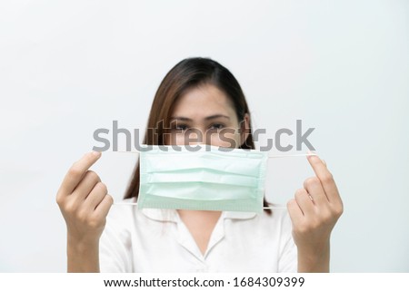 White shirt, woman looked at a medical mask to prevent the flu and the Covid-19 coronary virus, focus on the mask.