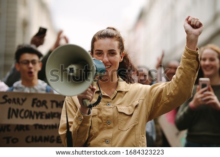 Modern urban woman protesting at a strike yelling her grievances into a megaphone. Female activist protesting with megaphone during a strike.