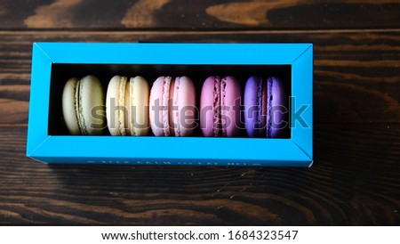 colorful macaroons in box on wooden background. Place for text. 