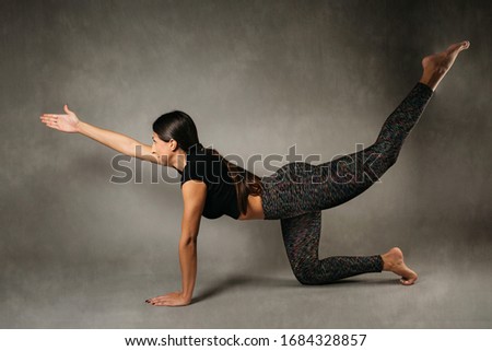 Beautiful young woman doing yoga, Donkey Kick exercise. Relaxation and meditation concept.