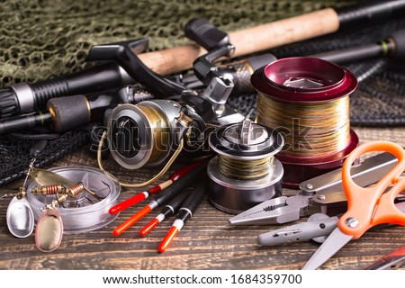 Fishing rods and spinnings in the composition with accessories for fishing on the old background on the table Royalty-Free Stock Photo #1684359700