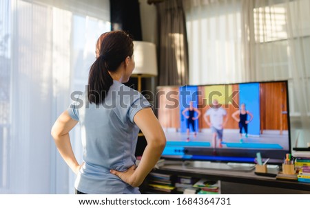 Video streaming Stay home.home fitness workout class live streaming online.Asian woman doing strength training cardio aerobic dance exercises watching videos on a smart tv in the living room at home. Royalty-Free Stock Photo #1684364731