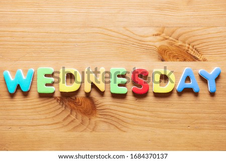 Wednesday word written with colorful letters on wooden table background, top view