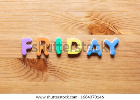 Friday word written with colorful letters on wooden table background, top view