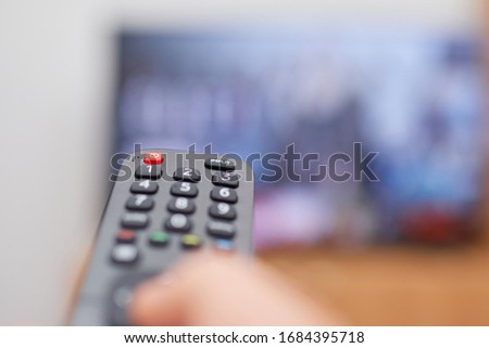 closeup of a tv remote control, background screen