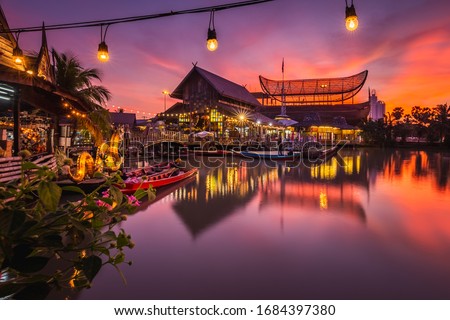 Sunset at famous Pattaya Floating Market which has traditional rowing boats. Villagers sell traditional foods and souvenirs. Royalty-Free Stock Photo #1684397380