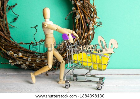 The Easter concept. Figure of a wooden man with a basket filled with eggs. In the background is a wooden rabbit and a sign of a Happy Easter and a wreath.
