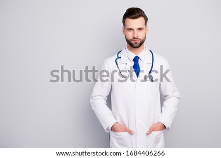 Portrait of his he nice attractive content smart clever qualified professional bearded guy doc holding hands in pockets isolated over light white gray pastel color background