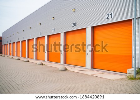 exterior of a commercial warehouse with orange roller doors Royalty-Free Stock Photo #1684420891