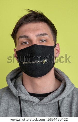 Calm. Close up caucasian man's portrait isolated on yellow studio background. Freaky male model in black face mask. Concept of human emotions, facial expression, sales, ad. Unusual appearance.
