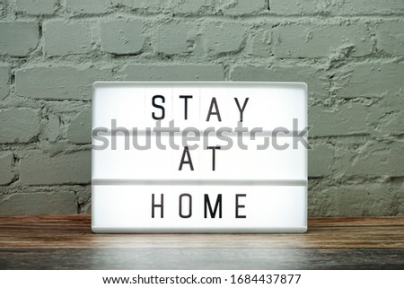 Stay at Home word letter in light box on white brick wall background