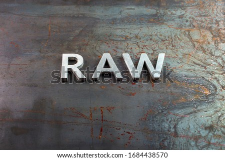 the word raw laid with silver metal letters on hot rolled steel sheet surface