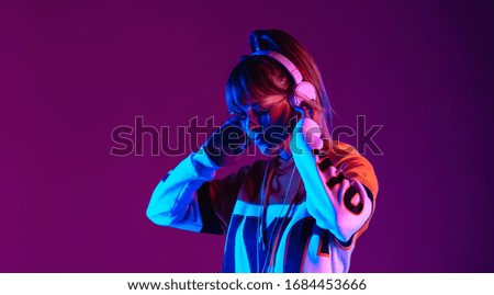 Calm girl wear stylish glasses headphones listen music at purple background. Royalty-Free Stock Photo #1684453666