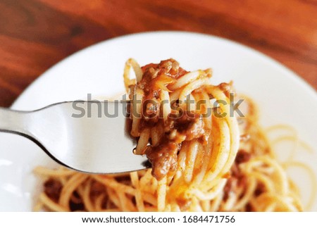 Spaghetti Bolognese with minced beef, onion, chopped tomato, garlic, olive oil, stock cube, tomato puree and Italian herb. Traditional Italian food in white plate with a fork. Selective focus. 