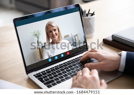 Head shot close up laptop screen view smiling attractive middle aged woman holding video call from home with male business partner, discussing working issues remotely online via videoconference app. Royalty-Free Stock Photo #1684479151