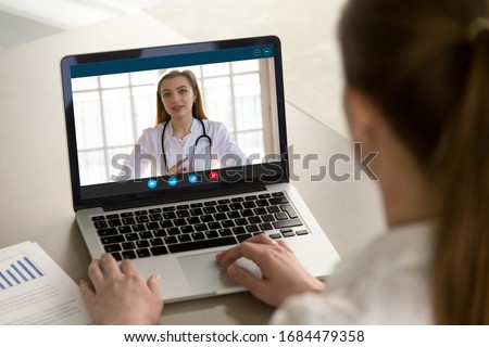 Shoulder view young woman consulting with family therapist doctor general practitioner online via video call on laptop after feeling first virus illness symptoms, medical insurance, covid19 outspread. Royalty-Free Stock Photo #1684479358