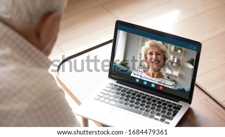 Side shoulder view older senior man looking at laptop monitor, talking speaking chatting with middle aged happy mature woman, communicating with wife online via video call, staying alone at home. Royalty-Free Stock Photo #1684479361