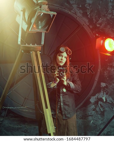 Beautiful steampunk teen girl  in goggles with old cameral, model in the style of a steampunk in a beautiful creative studio. Fashion, style