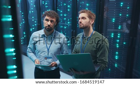 Team of professional data center engineers setting server hardware working on laptop coworking in digital server room. Webhosting. Technology concept. Royalty-Free Stock Photo #1684519147