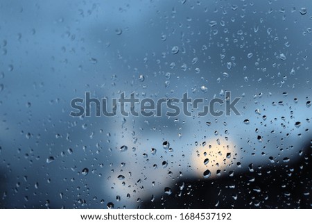 Rainy window in a blue dark view. Closeup view to a window in a rainy weather.