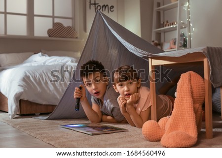 Scared little children reading bedtime story at home Royalty-Free Stock Photo #1684560496