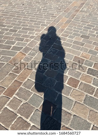 The shadow of a man on the cobblestones, the silhouette of a man, an ancient stone road