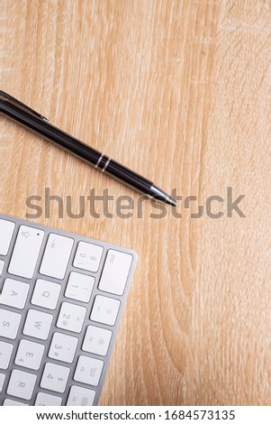 
Wooden office table with keyboard and pen, top view with copy space