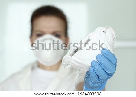 Coronavirus, N95 respirator, FFP2, COVID-19 concept. Medic, nurse with face mask and blue nitride  gloves  sharing protective respirator. Selective focus.  Royalty-Free Stock Photo #1684603996