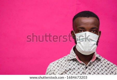a young african doctor isolated over pink background wearing face mask to prevent himself from the outbreak, disease and flu.
