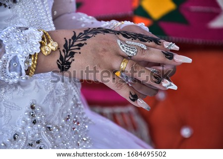 bride’s hand with gold rings and a bracelet, with oriental henna on the fingers, tradition