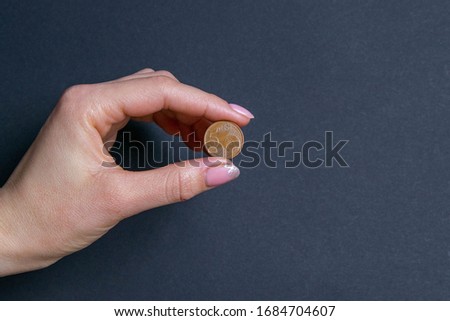 Hand sign by holding a coin, isolated on black background.