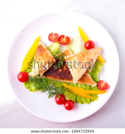 Pita triangles with cottage cheese, herbs, large tomatoes on a white plate