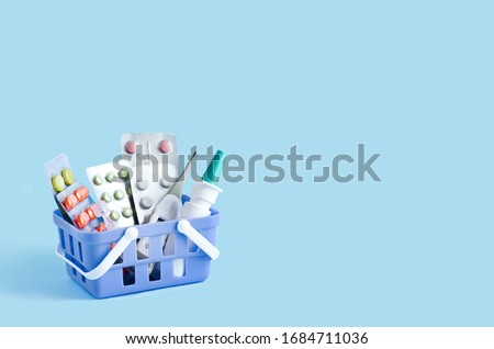 purchase, delivery of medicines to your home. home first aid kit for colds, illnesses, viruses, epidemics. online purchase of medicines. drugs in basket on blue background, copy space Royalty-Free Stock Photo #1684711036